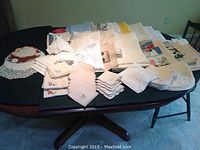 Wide arrangement of assorted table linens including napkins, doilies, placemats, tablecloths on a black table.