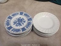 Stack of 16 blue floral plates by Melody and stack of 12 plain white plates by Myott Meakin placed on carpet