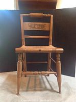 Full frontal view of the Hitchcock style wooden chair showing decorative stencil pattern and wicker seat.