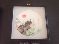 Photo of framed circular 3D wall art featuring two peacocks and a red sun on a natural background.