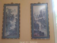Two vertical framed wall art pieces displaying traditional Chinese mountain scenes with mist and pagodas on a wall.