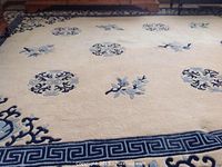 Full view of cream and blue wool rug showing field pattern and Greek key border