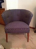 Front view of a blue upholstered chair with fan pattern fabric and wooden legs