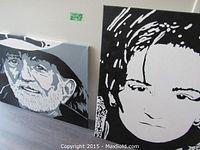 Both paintings leaning against a white wall on a floor