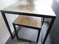 Two largest nesting tables nested inside each other showing square wood tops and black metal frames