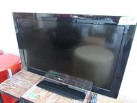 Front view of LG 32" flat screen TV on a wooden table, screen off.
