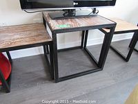 Three tables in row under wall-mounted TV, center table holding TV base