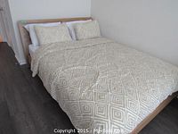 Full view of queen bed assembled with mattress, fitted sheet, comforter and pillows