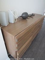 Front view of light brown wood dresser with two glass block lamps and one adjustable desk lamp on top