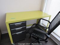 Photo of the yellow metal desk with black 3-drawer filing cabinet on casters and black swivel office chair next to a window.
