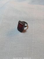 Ring displayed on light fabric background showing side angle of rectangular carnelian set in silver band.