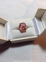 Top and angled view of the 10k gold ring featuring a large pink topaz stone inside a jewelry box.
