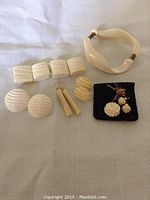 Full view of the seven antique carved bone jewellery pieces laid out on cloth. Includes bangles, earrings, and necklace.