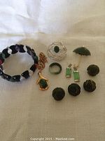 Various pieces of vintage jade and semi-precious stone jewelry including brooches, earrings, buttons, a ring, pendant necklace, and a bracelet.