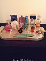 Full tray showing all 14 perfume bottles of varying designs and a nail manicure set with tools, arranged on a golden tray against a plain background.