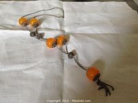 Y-shaped necklace laid flat showing five large amber beads and silver chain ending in an amber bead tassel