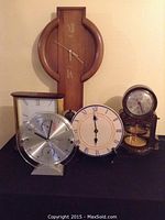 Five clocks arranged on black surface showing various models in photo.