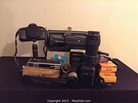 Full view of the lot showing the Canon EOS 650 camera, telephoto lens, vintage film cameras, film rolls, and accessories.
