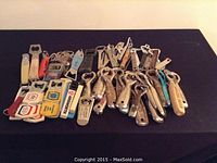 Full set of 75 vintage collectible bottle openers displayed on black surface.