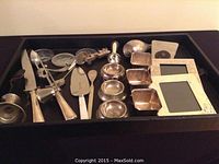 A tray with assorted silver plated decorative pieces including small bowls, photo frames, a candle holder, a pie server, letter opener, and other small items.