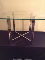 Front view showing the square glass top and chrome base with X-shaped legs.