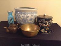 Overview of all five items in the lot including ceramic planter, black lacquered container, brass bowl, brass teapot, and cloisonné vase.