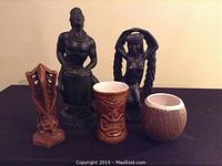 Front view of all five tiki decor items arranged on a black cloth.