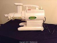 Side view of white Green Life twin gear juicer on black cloth