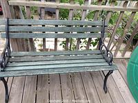 Front angle view of garden bench showing wood slat seat and back with black iron sides and legs.