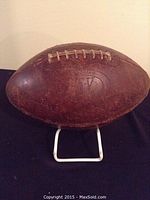 Full side view of the vintage Spalding leather football showing wear and official stamping.