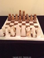 Frontal view of the full alabaster chess set with all pieces arranged on the board showing carved pieces and material.