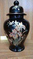Front view of black porcelain jar with floral design and lid