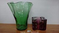 Green and purple glass vases on wooden surface