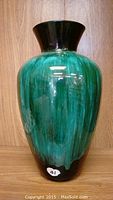 Front view of Blue Mountain glass vase showing green swirled body and black flared rim.