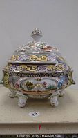 Front view of ceramic soup tureen showing hand-painted floral patterns, gold highlights, and ornate feet.
