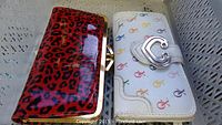 Photo showing two wallets side by side: left wallet is red leopard print with gold metal frame clasp, right wallet is white with colorful chain link design and silver buckle.