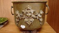 Full front view of the bronze bucket showing cherub relief decoration and patina finish.