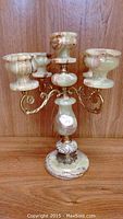 Full view of marble candleholder with three candle holders and brass arms on a wooden background.