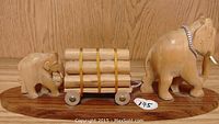 Overall view of the carved sandalwood set showing two elephants, wooden cart with logs on oval base.