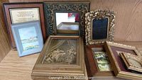 Collection of nine assorted picture frames in various styles and colors placed on a wooden surface.