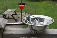 Full side view of the stainless steel food mill with red crank handle and pot grips.