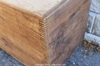 Close-up photo showing the dovetail joints on the corner of the chest, highlighting craftsmanship and wear on the wood.