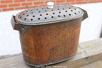 Antique copper asparagus steamer showing perforated lid and porcelain knob, side handles visible