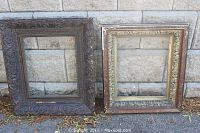 Two wooden picture frames shown side by side on a stone background, emphasizing size difference and carving details.