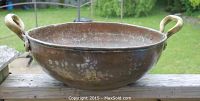 Side view of large hammered copper cauldron with brass handles shows natural patina and aged surface.