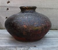 Front and side view of a sand blasted raku ware water pot with a dark and mottled textured surface.