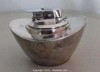 Front angled view of the mid-century Ronson table top cigarette lighter, showing sleek atomic shape and nickel finish.