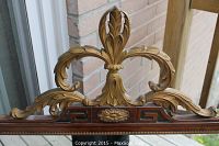 Close-up of the carved gilt pineapple decorative top of the mirror showing intricate scroll work and floral motif.