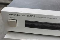 Close-up photo of the front left side of the tuner showing the power button and partial view of the tuning scale and brand name.