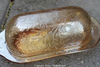 Top and side view of marigold carnival glass butter dish highlighting the floral and leaf embossed pattern.